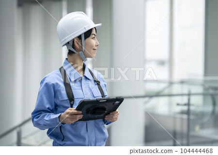 Woman in work clothes holding a tablet Building maintenance inspection image 104444468