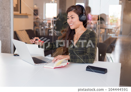 Smiling lady in headset speaking online in office 104444591