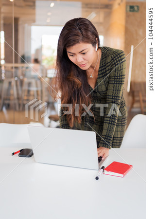 Focused woman browsing laptop at desk 104444595
