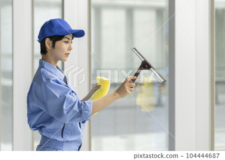 A woman in work clothes cleaning windows A woman in work clothes cleaning windows 104444687