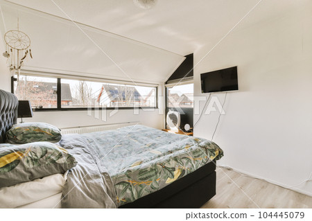 a bed in a room with a tv on the wall next to it and an air condition heater nearby 104445079