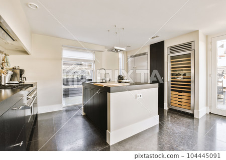 a modern kitchen with black and white appliances on the counters, along with an open door leading to another room 104445091