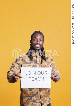 African american hr recruiter holding job offer sign, hiring candidate for business career opportunity standing in studio over yellow background. Advertisement with job application African american hr recruiter holding job offer sign, hiring candidate for business career opportunity standing in studio over yellow background. Advertisement with job application 104445392
