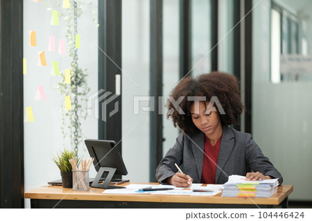 American African Woman working in the office with computer phone and Tablet. American African Woman working in the office with computer phone and Tablet. 104446424
