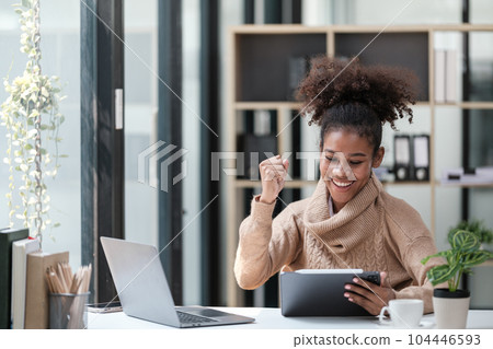 American African Woman working in the office with computer phone and Tablet. 104446593