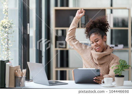 American African Woman working in the office with computer phone and Tablet. 104446698