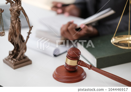 Lawyer office. Statue of Justice with scales and lawyer working on a laptop. Legal law, advice and justice concept.  104446917