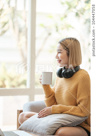 Portrait of Young Asian woman holding a hot cup of coffee, happy and relaxing time in living room. 104447058