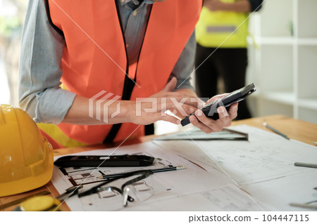 Close up of hand's architects working on blueprints in the office with drawing tools and a blueprint on his desk. 104447115