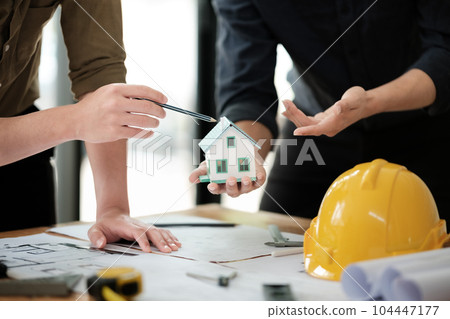 Engineers consulting team close up to design building blueprints paper for clients with building models to work at office. 104447177
