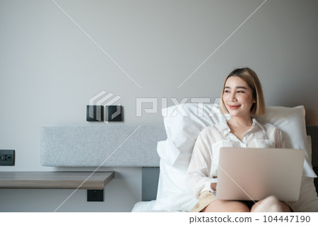Young beautiful asian woman playing laptop on a bed. Young beautiful asian woman playing laptop on a bed. 104447190
