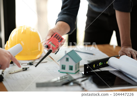 Engineers consulting team close up to design building blueprints paper for clients with building models to work at office. 104447226