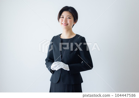 A woman in a black suit, white gloves A woman in a black suit, white gloves 104447586