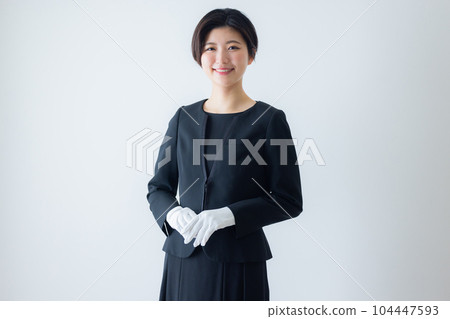 A woman in a black suit, white gloves 104447593