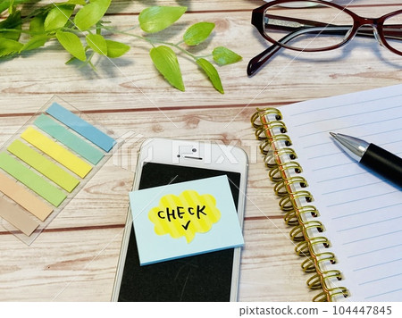 A sticky note written as check and a smartphone 104447845