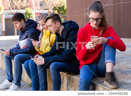 Teens with phones outdoors 104448208