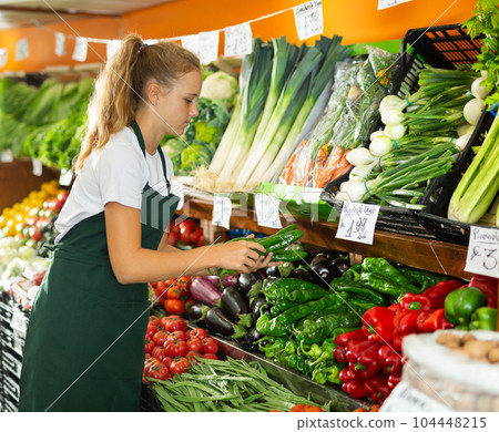 Young female seller holding pepper in grocery 104448215