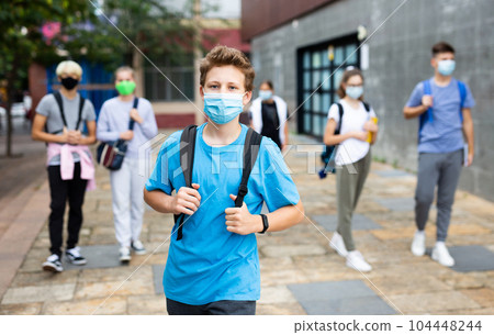 Young student in a protective mask going to college down city street 104448244
