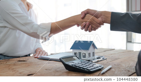 Real estate agents and customers shake hands to congratulate on signing a contract to buy a house with land and insurance Real estate agents and customers shake hands to congratulate on signing a contract to buy a house with land and insurance 104448380