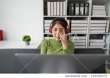 Woman plays on laptop on the sofa in her living room at home, she is resting on weekends after a hard day's work, she relaxes by watching movies and listening to music on her tablet. Holiday concept Woman plays on laptop on the sofa in her living room at home, she is resting on weekends after a hard day's work, she relaxes by watching movies and listening to music on her tablet. Holiday concept 104448475