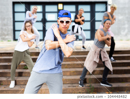 Confident teenager street dancer performing with group Confident teenager street dancer performing with group 104448482