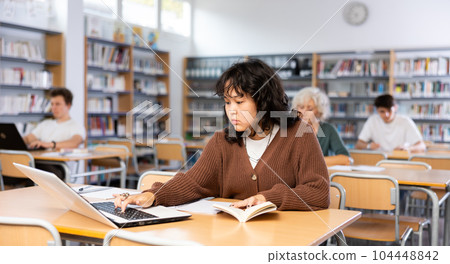 Fifteen-old-year schoolgirl doing homework in the school library 104448842