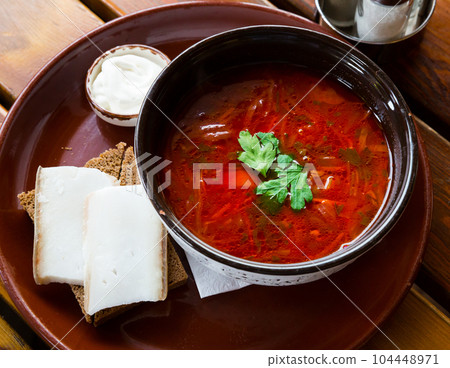 Traditional Ukrainian borsch with sour cream in bowl, bread with bacon 104448971