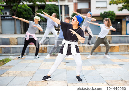 Teen girl dancing modern choreography with group outdoors Teen girl dancing modern choreography with group outdoors 104449060