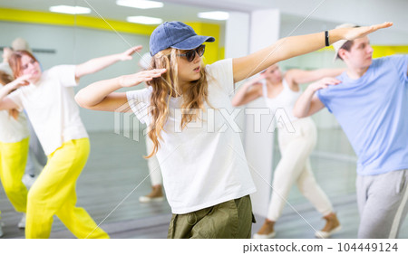 Teenage girl in sunglasses and cap training breakdance Toprock moves in dance hall 104449124