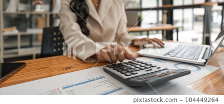 Close-up of businesswoman hands using a calculator to check company finances and earnings and budget. Business woman calculating monthly expenses, managing budget, papers, loan documents, invoices Close-up of businesswoman hands using a calculator to check company finances and earnings and budget. Business woman calculating monthly expenses, managing budget, papers, loan documents, invoices 104449264