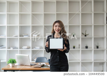 image of a business woman holding digital tablet with blank white desktop screen in office 104449500