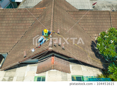Worker man repairing eaves and tile of the old roof.. 104451615