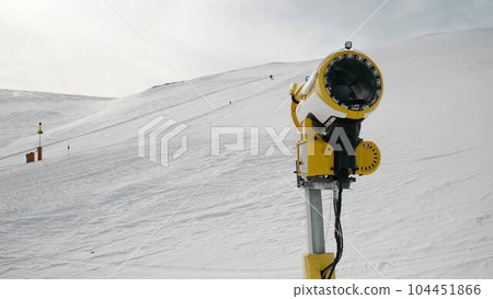 Livigno, Italy - February 21, 2022: Snow making machine, snow cannon at ski resort Livigno, Italy at sunny winter day and skiers 104451866