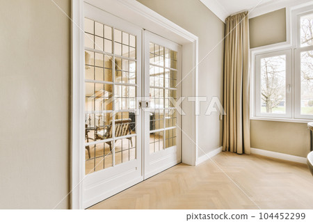 a living room with wood flooring and white trim on the walls, along an open door that leads to a dining area 104452299