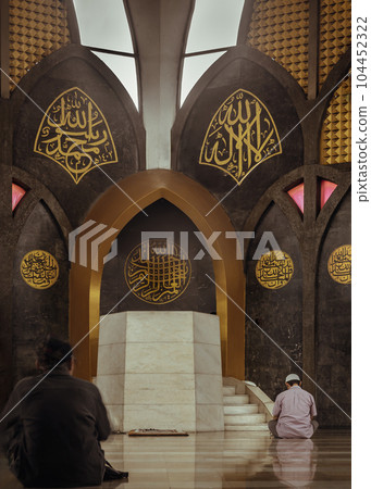Religious muslim men sits and recite prayers for God on the floor in the Central Mosque and Islamic Center of Thailand. Religious muslim men sits and recite prayers for God on the floor in the Central Mosque and Islamic Center of Thailand. 104452322