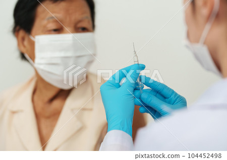 doctor make injection Covid-19 or coronavirus vaccine to senior patient in medical mask doctor make injection Covid-19 or coronavirus vaccine to senior patient in medical mask 104452498
