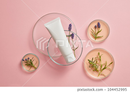 Against the pink background, an empty plastic bottle decorated with some petri dishes containing fresh lavender and essence. Mockup with blank space for design, advertising and branding product Against the pink background, an empty plastic bottle decorated with some petri dishes containing fresh lavender and essence. Mockup with blank space for design, advertising and branding product 104452995