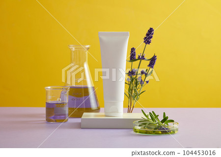 Front view of white cosmetic bottle without labeled placed on podium with fresh lavender flower on yellow background. Mockup for design, organic cosmetics and beauty products concept 104453016