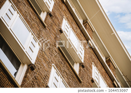 a brick building with white shutters on the windows and an airplane flying in the sky above it, as seen from below a brick building with white shutters on the windows and an airplane flying in the sky above it, as seen from below 104453097