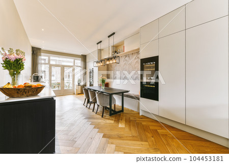 a modern kitchen with wood flooring and white cabinets in the center of the room is a bowl of fruit a modern kitchen with wood flooring and white cabinets in the center of the room is a bowl of fruit 104453181
