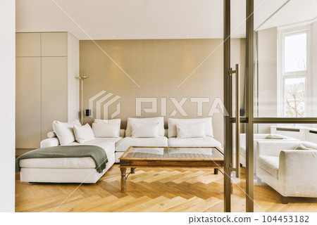 a living room with wood flooring and white couches in the center of the room is an open door 104453182