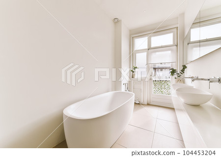 a white bathroom with two sinks and a large bathtub in the center of the photo is an open window a white bathroom with two sinks and a large bathtub in the center of the photo is an open window 104453204