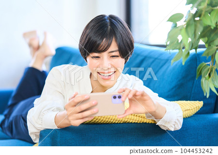 Young woman lying on the sofa, living room, smartphone Young woman lying on the sofa, living room, smartphone 104453242