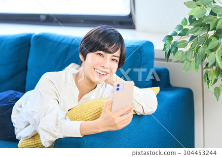 Young woman lying on the sofa, living room, smartphone Young woman lying on the sofa, living room, smartphone 104453244