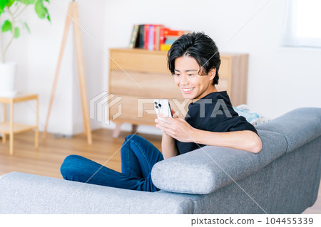 A young man operating a smartphone - Stock Photo [104455339] - PIXTA