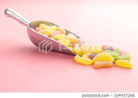 Mix of fruity jelly candy in scoop on pink background. 104457266