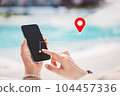 Woman hand using smart phone with navigator location point at tropical sunset beach abstract background. Technology interenet and travel adventure concept. Vintage tone filter effect color style. 104457336