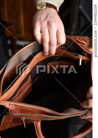 top view of open empty leather bag in mans hands top view of open empty leather bag in mans hands 104460284