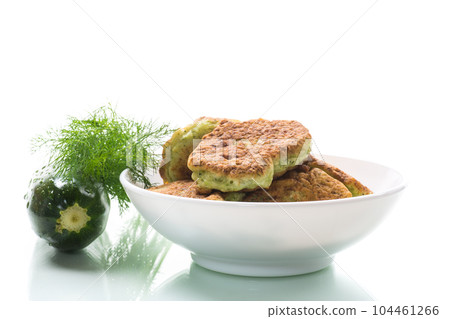 fried zucchini pancakes with herbs, in a plate . 104461266