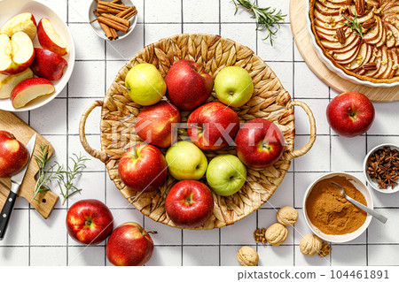 Apple. Fresh raw juicy red and green apples in a basket on a kitchen table with ingredients for cooking Thanksgiving autumn season apple pie, top view 104461891